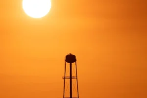 Water tower silhouetted against a hazy summer sky, illustrating the St. Tammany Parish heat advisory