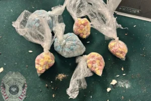 Bags of seized narcotics, including pills and powder, displayed next to a Slidell Police Department badge