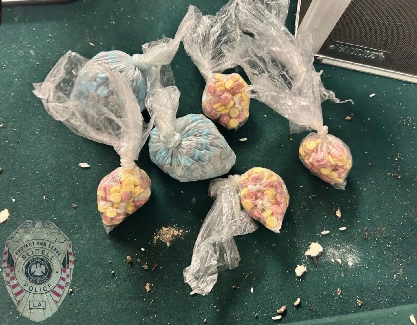 Bags of seized narcotics, including pills and powder, displayed next to a Slidell Police Department badge
